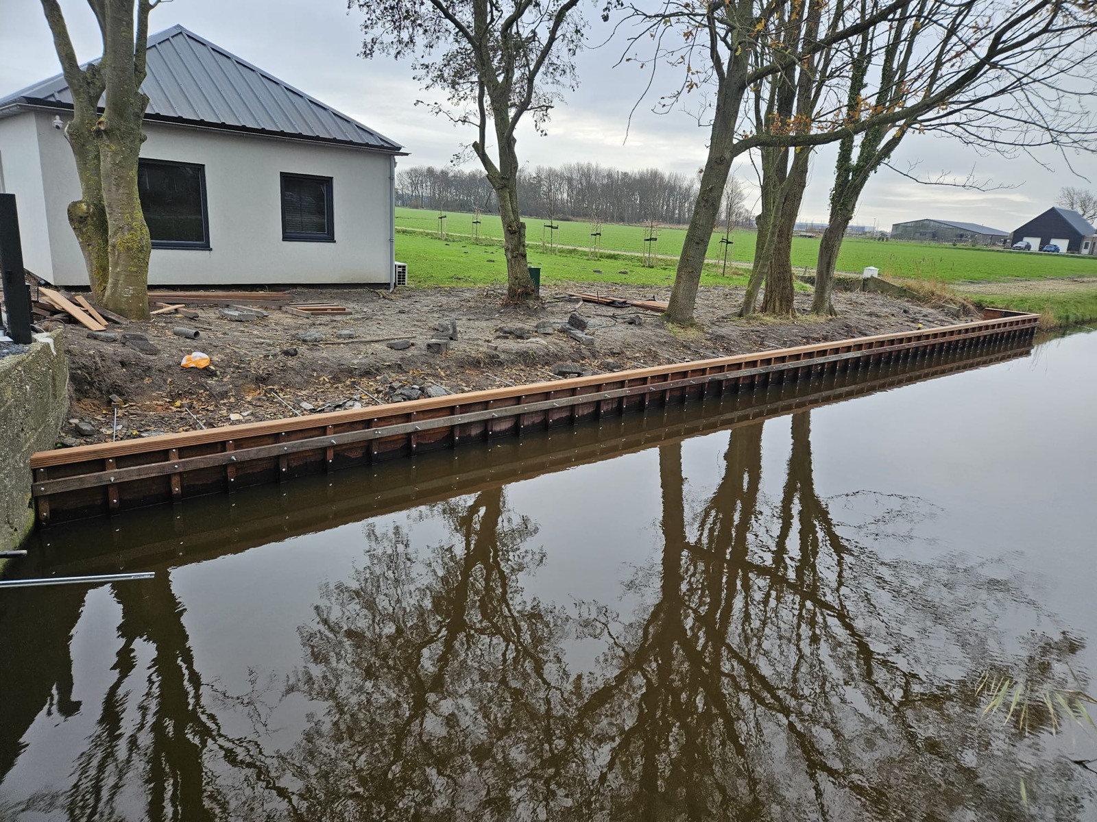Houten beschoeiing langs een kanaal bij een woning